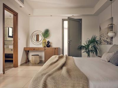 Gemütliches Schlafzimmer mit modernem Dekor, Holzkommode, Pflanzen und Blick ins Badezimmer.