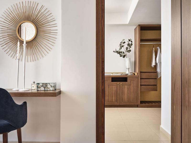 Moderner Flur mit dunklem Holzrahmen, weißem Wandspiegel und blauem Polsterstuhl.