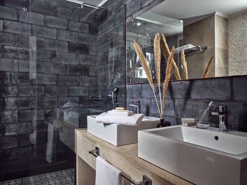 Modernes Badezimmer mit eckiger weißer Keramikspüle, Holzablage und dunklen Wandfliesen.