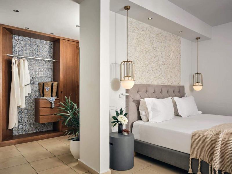 Modernes Hotelzimmer mit Doppelbett, gemütlichen Lampen und offenem Kleiderschrank mit Kleidung.