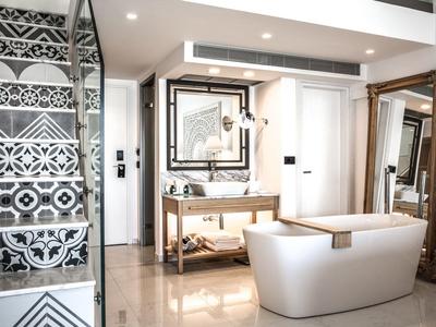 Moderne badkamer met vrijstaand bad, glazen douche met patroon, grote spiegels en strakke armaturen.