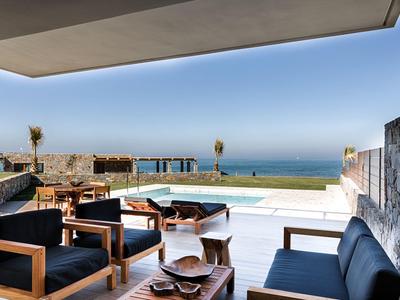 Moderne buitenzitplek met houten meubels en uitzicht op zee bij luxe hotelterras.