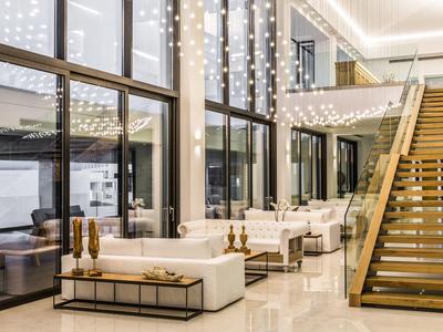 Moderne hotellobby met grote ramen, elegante zitjes, decoratieve verlichting en houten trap.