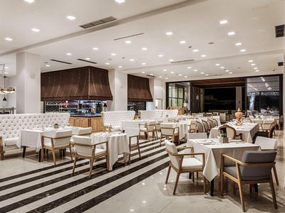 Modernes Restaurant mit gedeckten Tischen und Stühlen in hellem Ambiente und gestreiftem Bodenbelag.