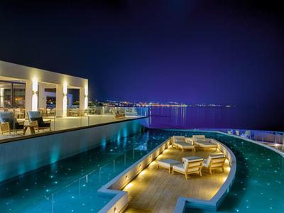 Luxe buitenzwembad en loungegebied met uitzicht op stadslichten in de nacht.