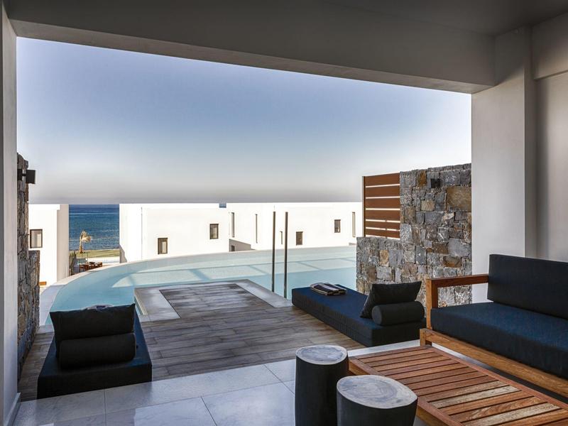 Modern terras met zitgedeelte kijkt uit op infinity pool en uitzicht op zee bij een luxe hotel.