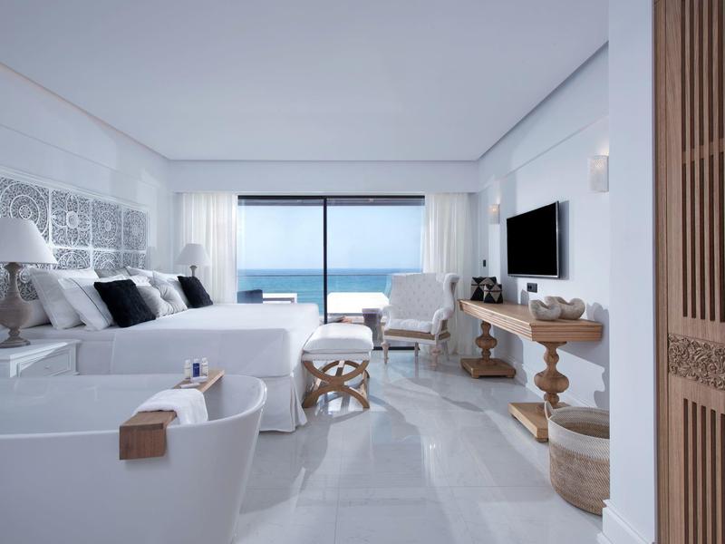 Moderne hotel eetzaal met witte tafelkleden, beklede stoelen en gestreepte vloertegels.