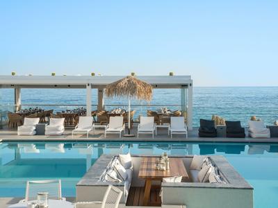 Nowoczesny basen z leżakami i widokiem na morze pod czystym niebem.