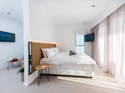 Lichte, moderne slaapkamer met groot bed, raam met gordijnen en wand-tv.