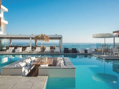 Nowoczesny obszar basenowy z miejscami do siedzenia i widokiem na morze przy czystym niebie.