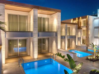 Complesso alberghiero moderno con piscina illuminata e balcone di notte.