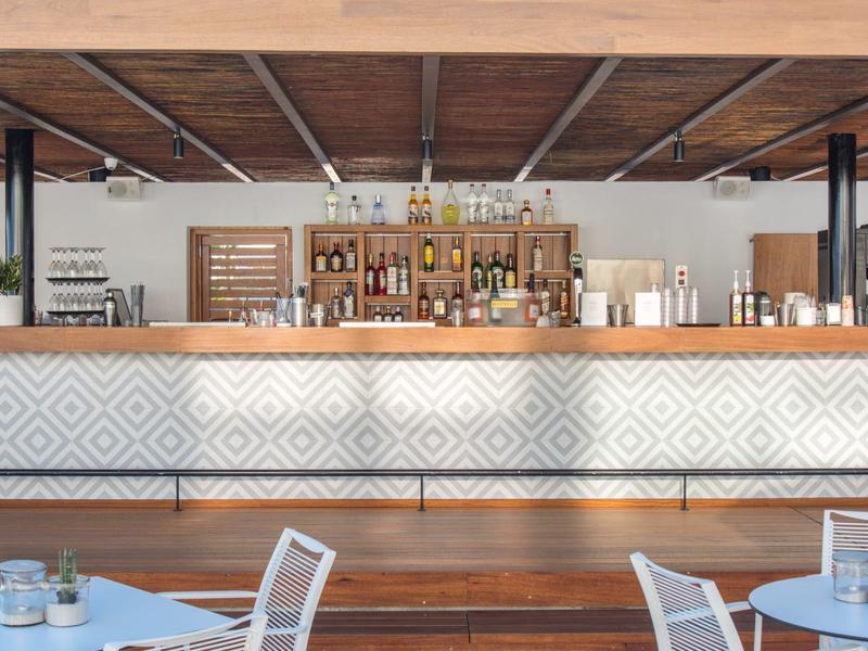 Moderne hotelbar met houten plafond en witte patroonbalie.