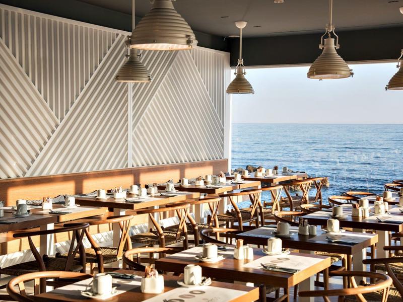 Modern restaurant met houten tafels en zeezicht door grote ramen