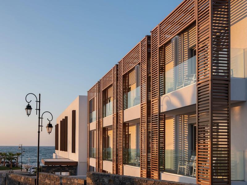 Modern hotelgebouw met houten panelen en zeezicht bij zonsondergang