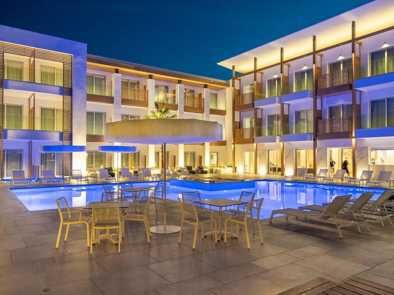 Modern hotel met verlichte zwembadgebied en zitplaatsen in de avond.