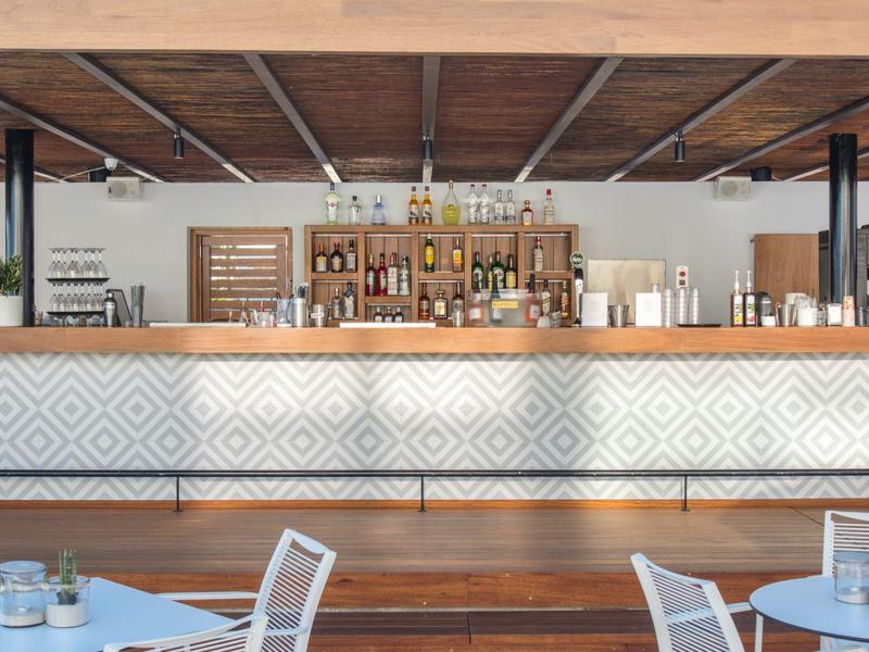 Moderne hotelbar met houten plafondlijst en geometrisch patroon op het paneel