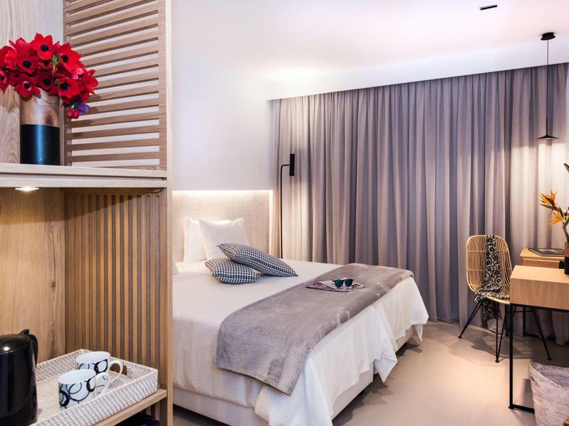 Moderne hotelkamer met bed, bureau en bloemendecoratie.