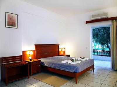 Schlichtes Hotelzimmer mit Doppelbett, Nachttischen und Blick auf eine Terrasse.