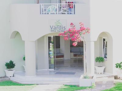 Vstup do bílé budovy se zeleným trávníkem a květináči