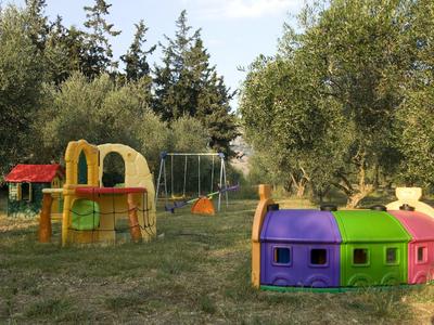Kinderspielplatz mit buntem Spielhaus, Rutsche, Schaukeln und umgeben von Bäumen auf Wiese.