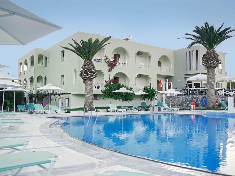 Moderne Hotelanlage mit blauem Pool, Palmen und weißen Sonnenschirmen bei klarem Himmel.