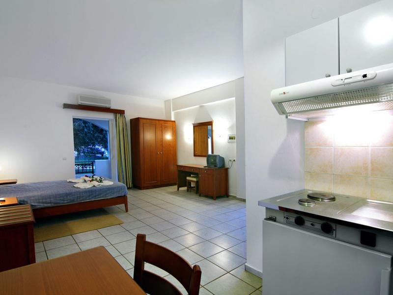 Helles Hotelzimmer mit Küchenbereich, Bett, Schrank und Schreibtisch.