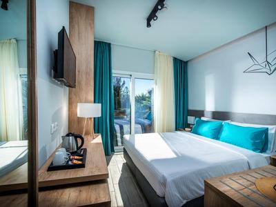 Camera d'hotel moderna con letto matrimoniale, TV, scrivania e vista sul balcone.