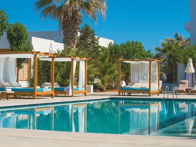 Einladender Außenpool mit hölzernen Sonnenbetten und Palmen unter klarem blauem Himmel.