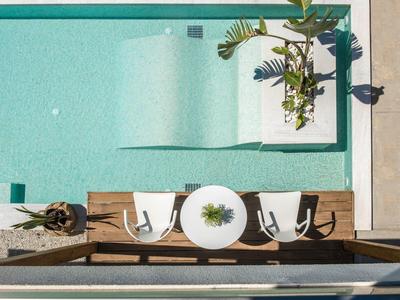 Terrazza in legno con tavolo rotondo e due sedie accanto a una piscina turchese.