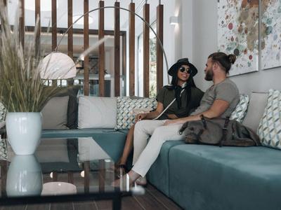 Zwei Personen entspannen auf einer modernen Couch in einem stilvollen Hotel mit dekorativen Kissen.