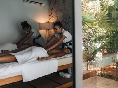 Un uomo riceve un massaggio in una stanza d'hotel moderna con luce soffusa.