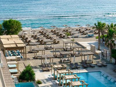 Piscina con lettini e ombrelloni davanti al mare, atmosfera da vacanza al mare.