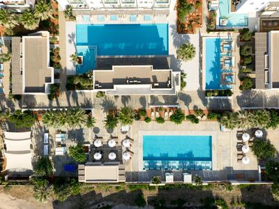 Vista aerea di due piscine all'aperto circondate da sdraio e edifici.