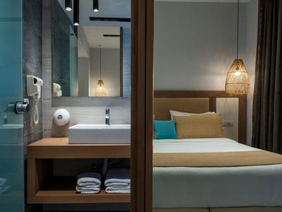 Camera d'hotel moderna con letto matrimoniale, biancheria bianca e bagno annesso.