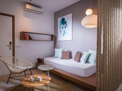 Nowocześnie urządzone pokoje hotelowe z kanapą, poduszkami i dekoracyjnym obrazem na ścianie.