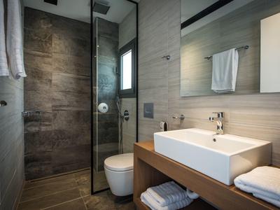 Bagno moderno con doccia, lavabo rettangolare, wc e asciugamani.