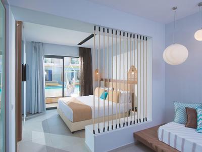 Modernes Hotelzimmer mit hellen Wänden, Doppelbett und großem Fenster mit Vorhängen.