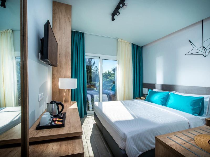 Camera d'hotel moderna con letto matrimoniale, TV, scrivania e vista sul balcone.