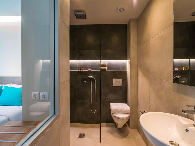 Bagno moderno con doccia, lavabo e WC, vista sulla camera con letto blu.