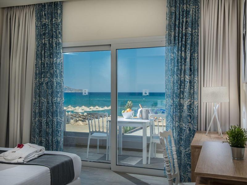 Camera d'hotel con vista mare, balcone e mobili bianchi, atmosfera luminosa e tranquilla.