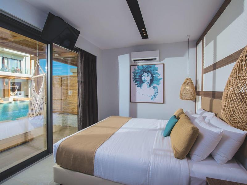 Camera d'hotel moderna con letto matrimoniale e vista piscina attraverso porta scorrevole.