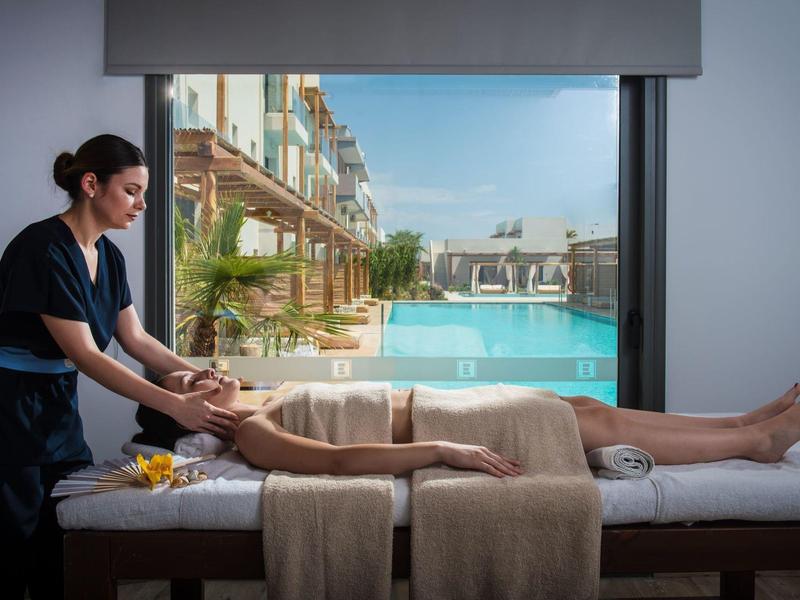 Donna che riceve un massaggio spa con vista su piscina esterna e edifici moderni.