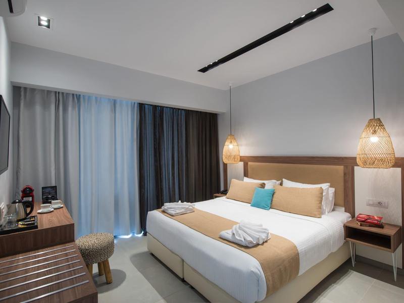 Camera d'hotel moderna con letto matrimoniale, illuminazione calda e mobili in legno.