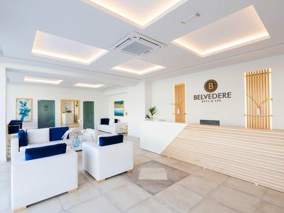 Helle Hotelrezeption mit modernem Holzempfangsschalter und weißen Sesseln mit blauen Kissen