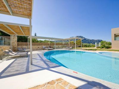 Piscina esterna moderna con lettini e vista sulle montagne sotto un cielo limpido.
