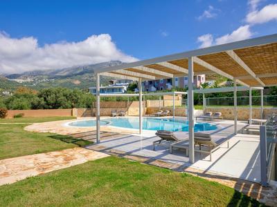 Area piscina moderna con copertura e ombrelloni in un ambiente esterno curato.