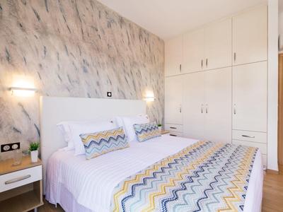 Světlá ložnice s manželskou postelí a velkými vestavěnými skříněmi v moderním stylu.