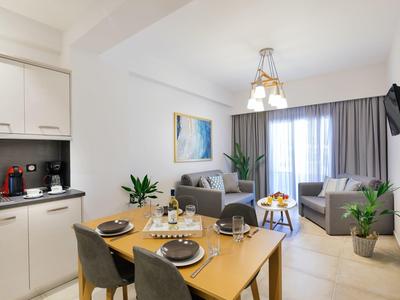 Světý obývací pokoj s jídelním stolem, pohovkou, křesly a kuchyňským koutem v rekreačním apartmánu.