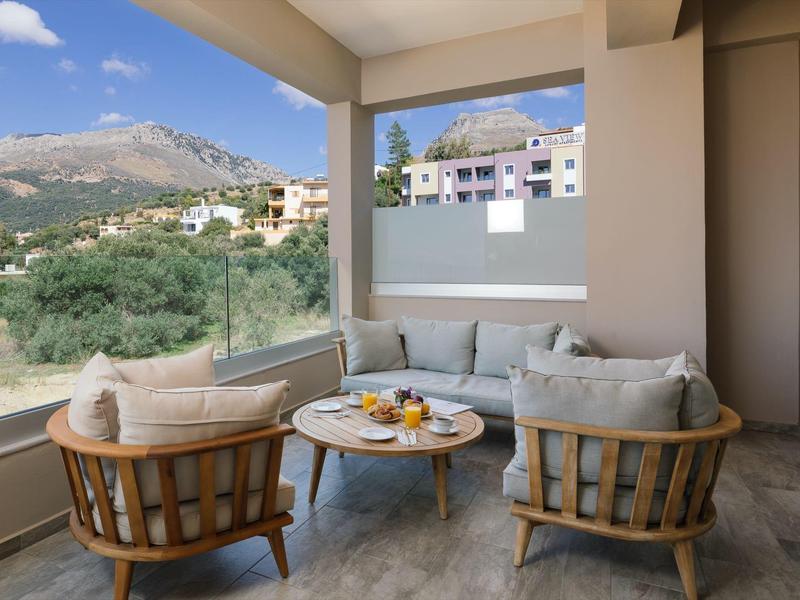 Balkon s pohodlným posezením a výhledem na hory v hotelovém pokoji.