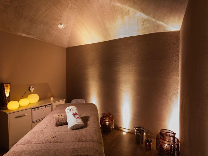 Pohodlná ošetřovací místnost s masážním stolem, tlumeným osvětlením a dekoračními lampami.